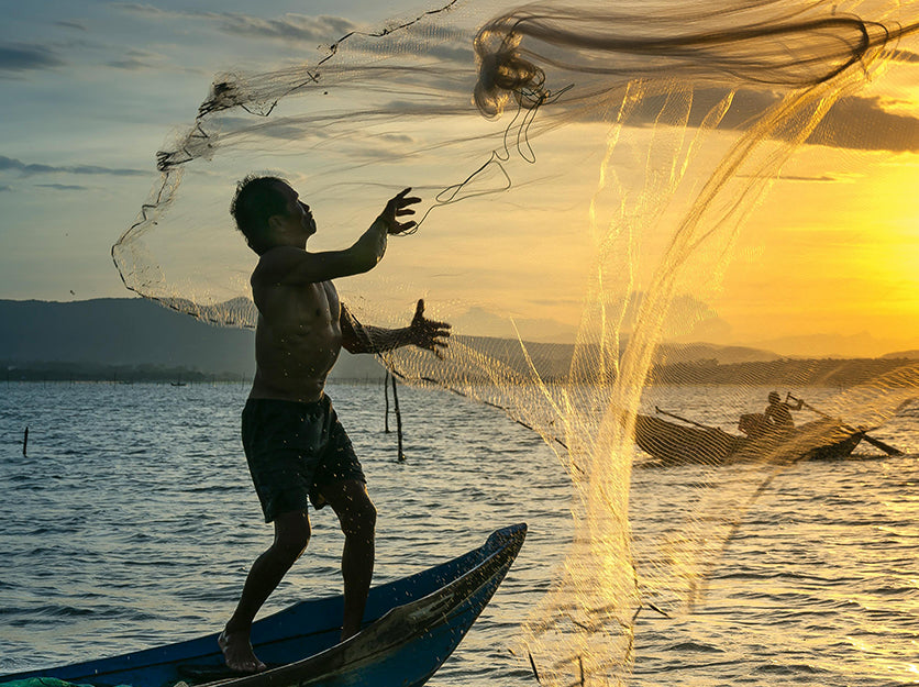 Fisherman throwing net at sunset in Vietnam